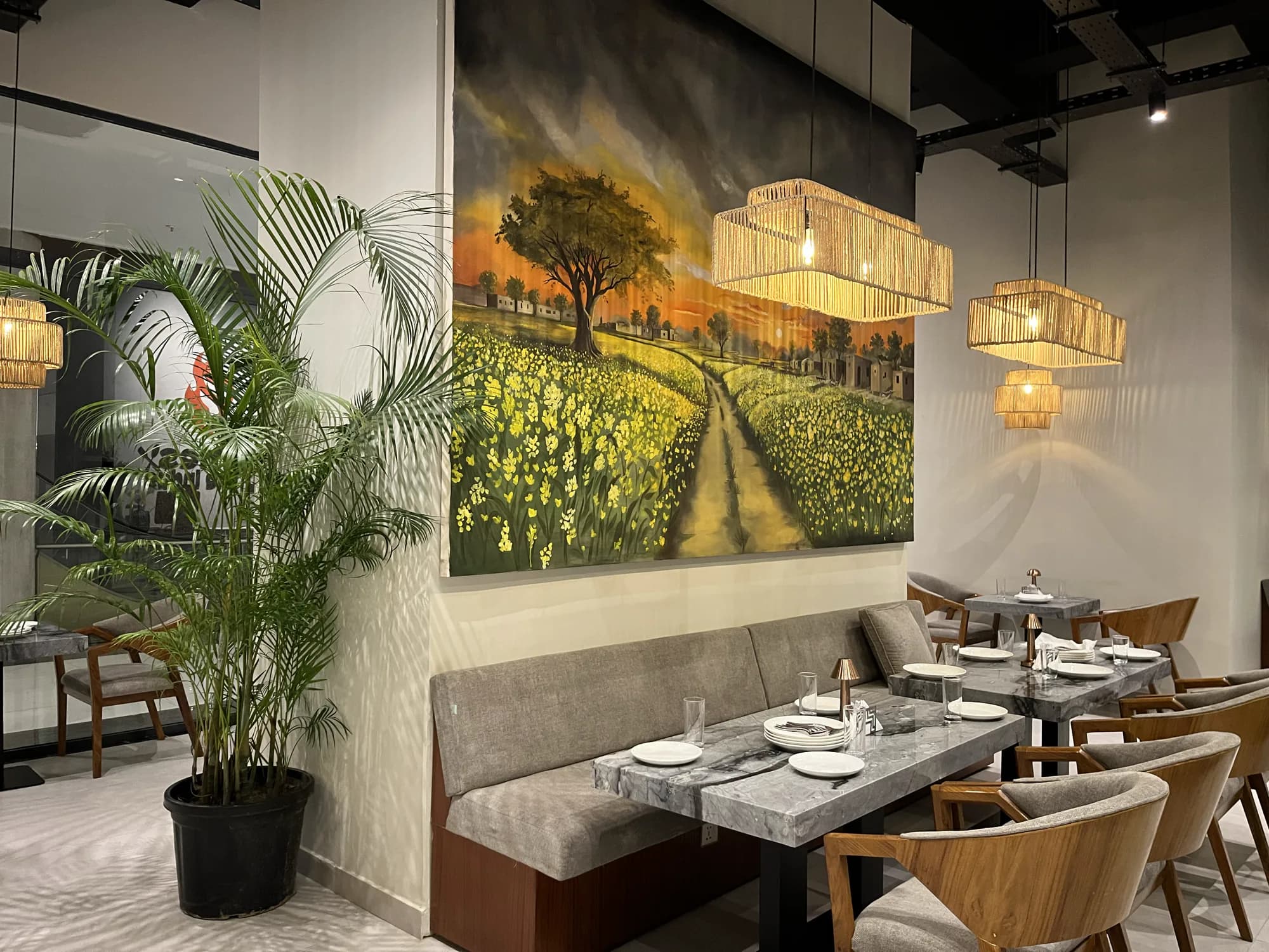 A painting of a mustard field above the corner booth at Flames by the Indus