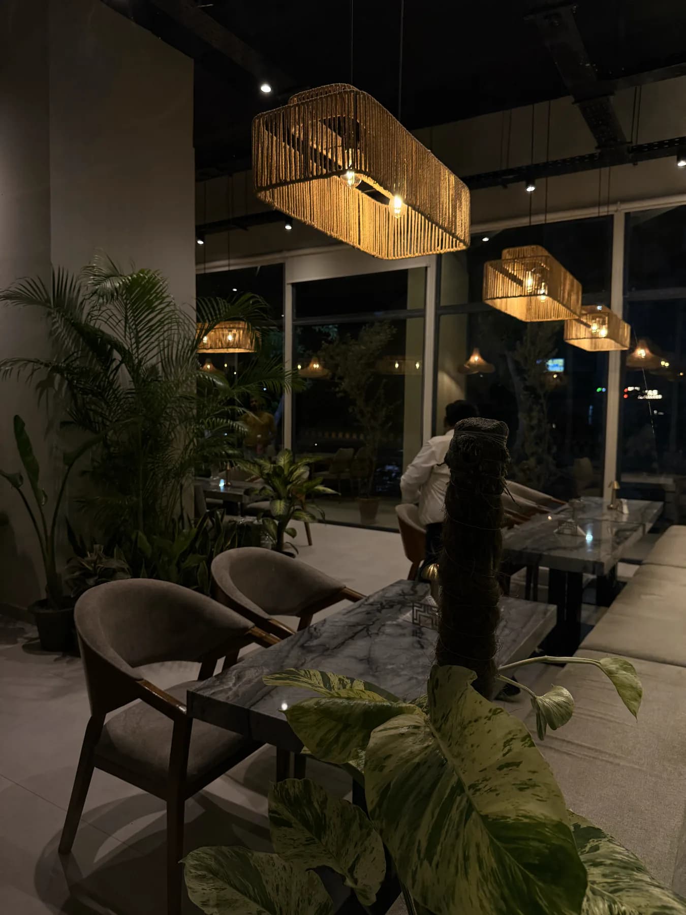 Woven rattan pendant lights above a marble table at Flames by the Indus