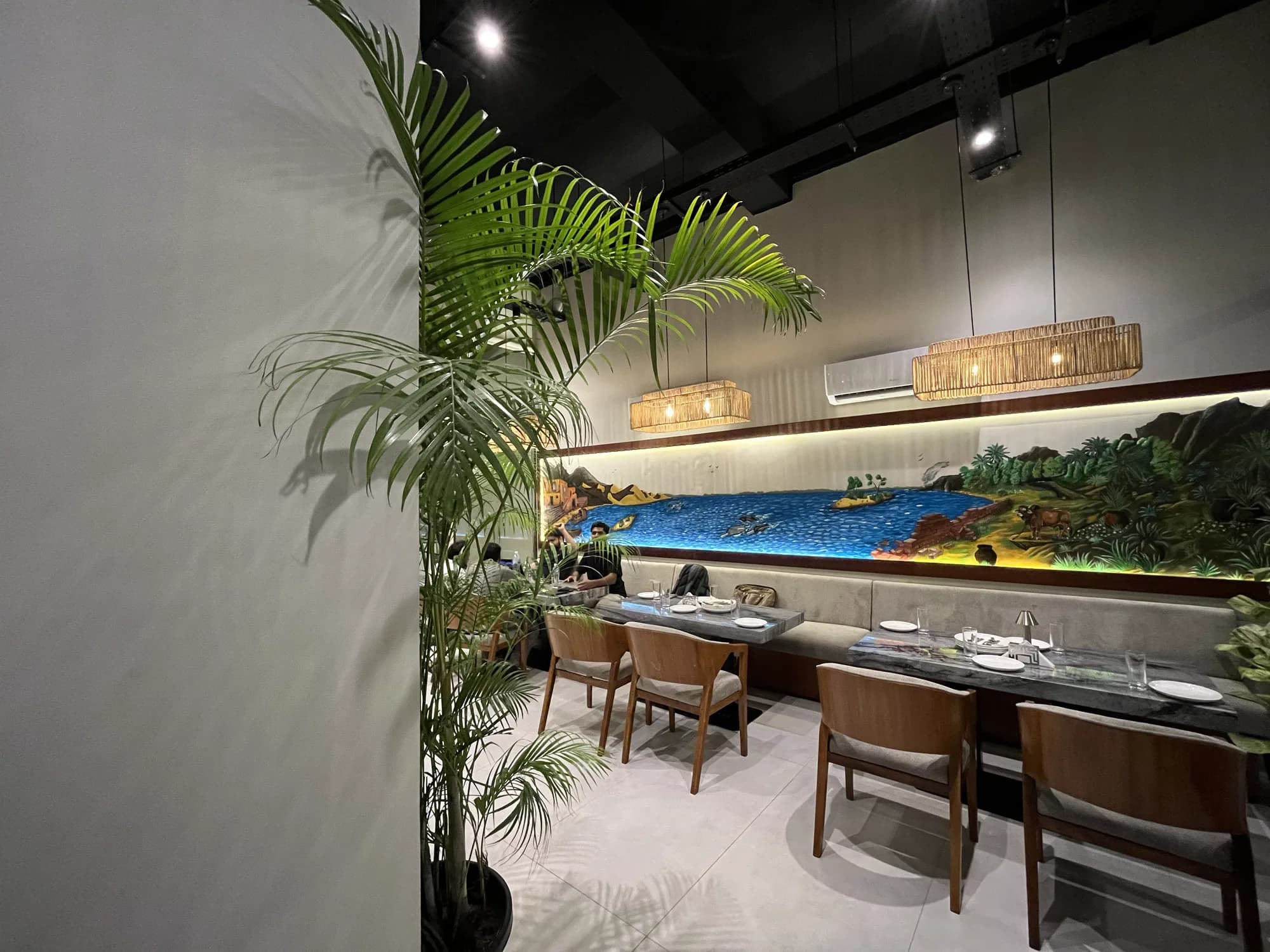 A palm beside the Indus mural, tables laid for service